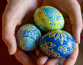Three handmade decorated Easter eggs in woman palms