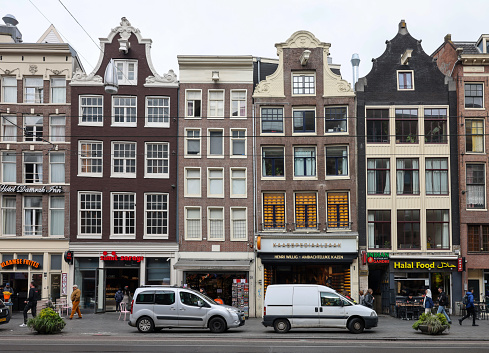 Amsterdam, Netherlands - April 21, 2023: Typical gabled houses on Damrak street in Amsterdam, Holland, Netherlands