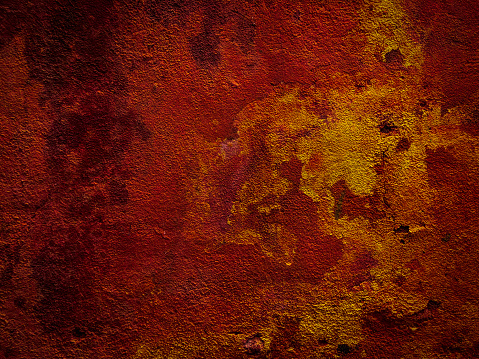 Horizontal closeup photo of an old, rendered wall with mustard yellow, orange and deep red colours on a house in the old centre of Aix-en-Provence, south of France.