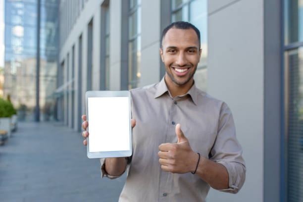 istock Satisfied arab male making thumb up gesture while holding digital tablet with blank screen on urban background. Modern device user recommending and approving new useful commercial application 2028494719