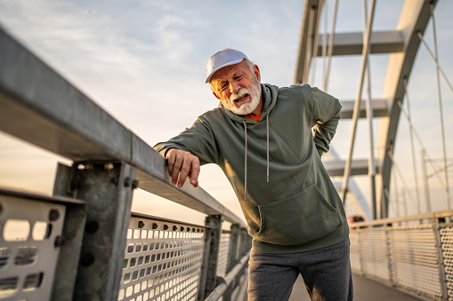 The image shows an elderly man experiencing back pain while running, the image reminds of the importance of listening to your body during training