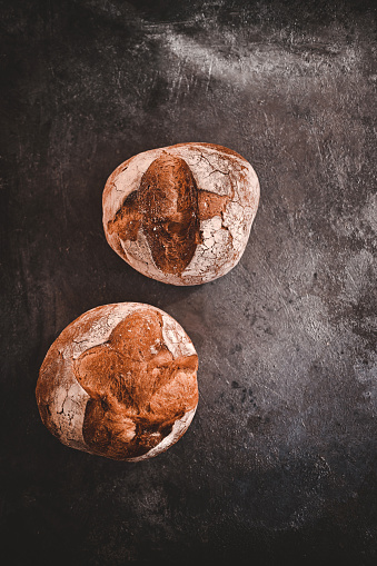 Two rustic breads on a concrete background.
