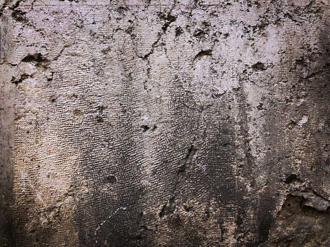 Horizontal closeup photo of an old, weathered, discoloured, blacik and grey stained stucco rendered wall of a house in the old centre of Aix-en-Provence, south of France.