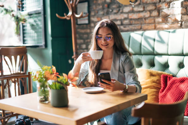istock A young woman is sitting alone in a cafe, using the phone and drinking coffee. 2028524742