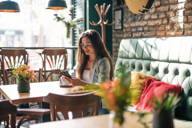 istock A young woman is sitting alone in a cafe, using the phone and drinking coffee. 2028526832