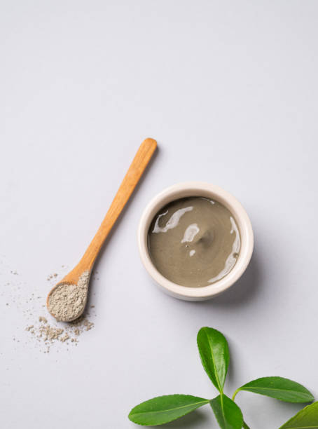 istock Blue clay in a bowl and spoon on a light background with leaves. 2028536429