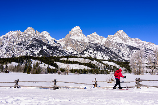 Skier skiing in front of the Grand Teton Range in winter in Grand Teton National Park, Wyoming.