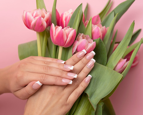 Beautiful female hands with spring manicure nails with pink tulips