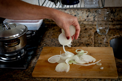 Hand holding sliced onions on a cutting board. Food seasoning.