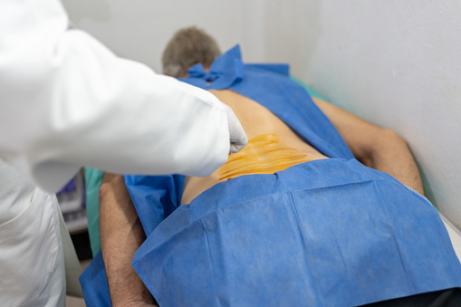 doctor preparing a patient for infrared treatment with heat applying gel on the back, treatment for back injury pain or kidney disease