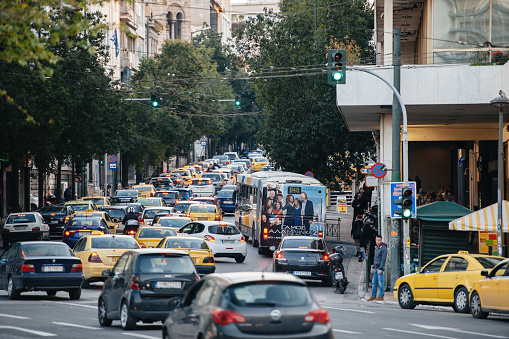 Athens, Greece - Mar 29, 2016: Busy lanes with yellow taxis and cars on the Ploutarchou avenue in central Athens with Cosmote mobile operator store in background traffic jam driving in Greece