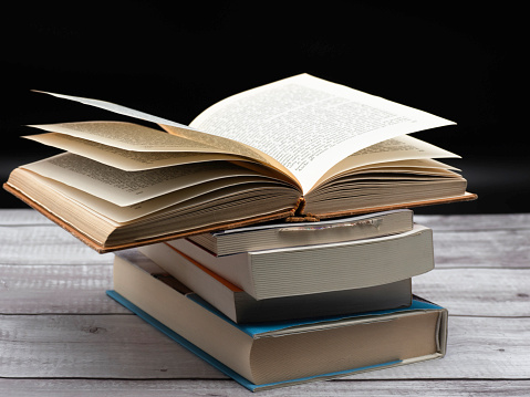 Vintage old hardback books, diary, fanned pages on wooden desk table and grunge background Daylight. Books stacking. Back to school. Copy Space. Education background