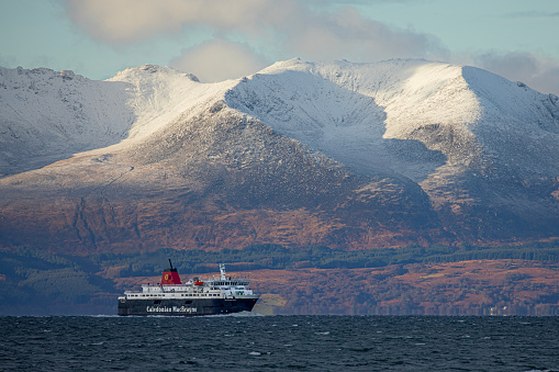The Arran ferry, MV Caledonian Isles,  Eileanan Chaledonia, in front of the Island of Arran in the Firth of Clyde off North Ayrshire. The ferry, which is operated by Caledonian MacBrayne (CalMac) carries vehicles and foot passengers between Brodick on the island and Ardrossan on the mainland.