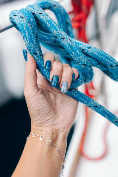 istock Woman's hand with blue manicure holding blue yacht rope. 2028734951
