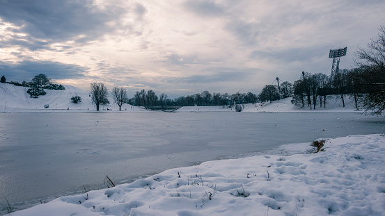 Frozen lake at Olympic Park, Munich, during winter with snow covering the ground.