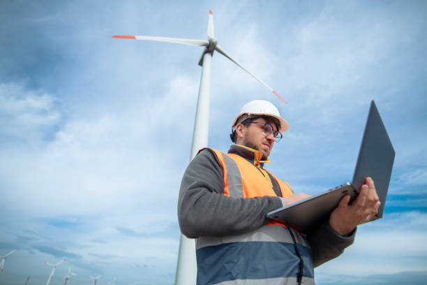 istock Engineer working on laptop in a wind turbine farm. 2028852180