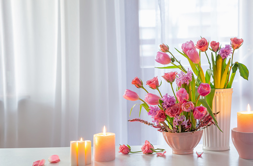 spring flowers with burning candles on background window