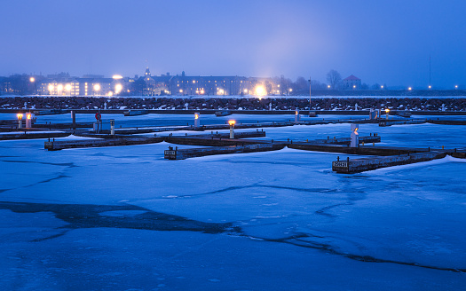 Looking across the ice covered marina in Kingston to The Royal Canadian Military College on a cold and Foggy winter evening.