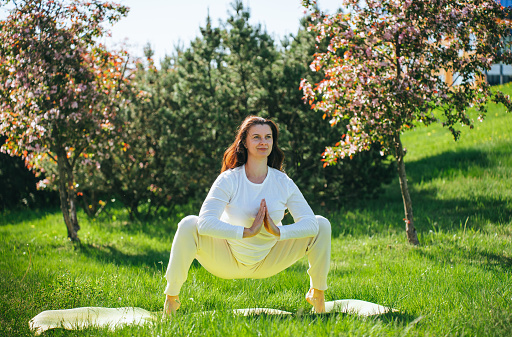 Woman practicing yoga in a garden, sunlight, peaceful, wellness.