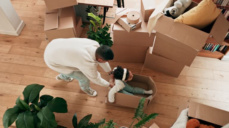 Girl, playing and box with father in top view at new home for game with entertainment on floor. Kid, parent and cardboard for celebration with investment at property for relocation with mortgage.