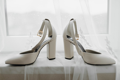 White elegant shoes. A pair of classic white shoes standing on a window sill on a white background. Fashion. Style. Wedding photo