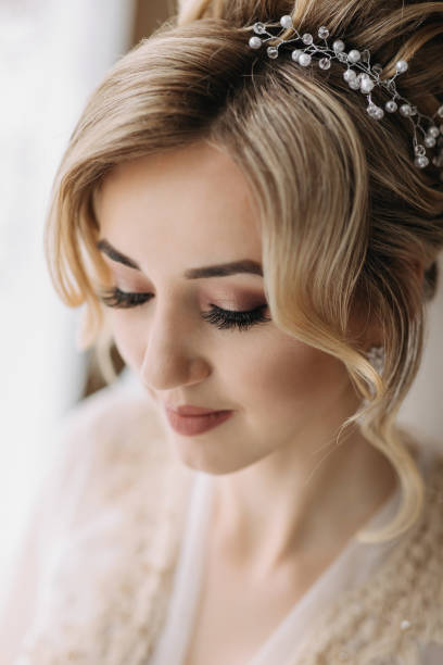 istock Blonde Bride with elegant hairstyle and tiara, in mantle, standing looking down. Nice makeup. Wedding photo 2028991172