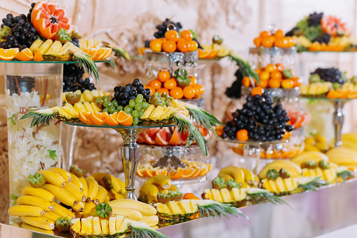Fruit bar. Table with fruits, bananas, grapes. orange and pineapple. Beautiful table setting, fruit on stands, selective focus