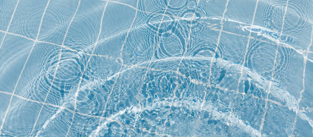 istock Clear water surface with ripple wave splashes and drops in swimming pool. Abstract turquoise or blue texture water wave and sunlight shadow reflections for background. 2028996131