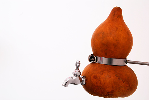 concept of saving water, water tap attached to an authentic Mexican gourd, on white background with space for text