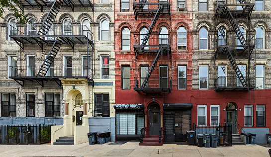 Old fashioned New York City apartment building with decorative roof cornice and external fire escapes