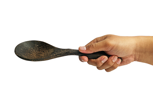 hand holding wooden spoon isolated on a white background.