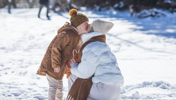 Winter weekend. Mother and two sons  in warm winterwear walking  while having fun in winter forest among trees
