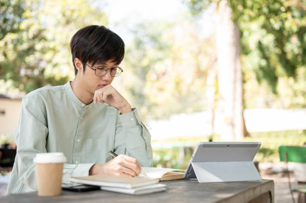 istock A smart Asian male university student is doing homework or studying online on his digital tablet. 2029166020