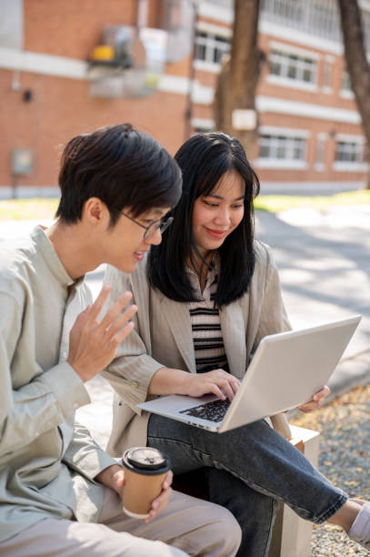 istock Two smart Asian students are collaborating on a project while sitting together in the park. 2029182757