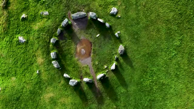 Top down aerial drone shot rising up over the Drombeg Stone Circle, an ancient historical landmark in County Cork, Ireland
