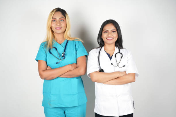 istock two nurses with scrubs are standing by each other and posing for the camera 2029404067