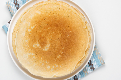 Stack of fresh thin pancakes on white table, top view.