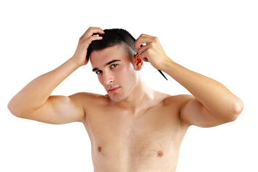 Portrait of handsome young man combing his hair on white background close up