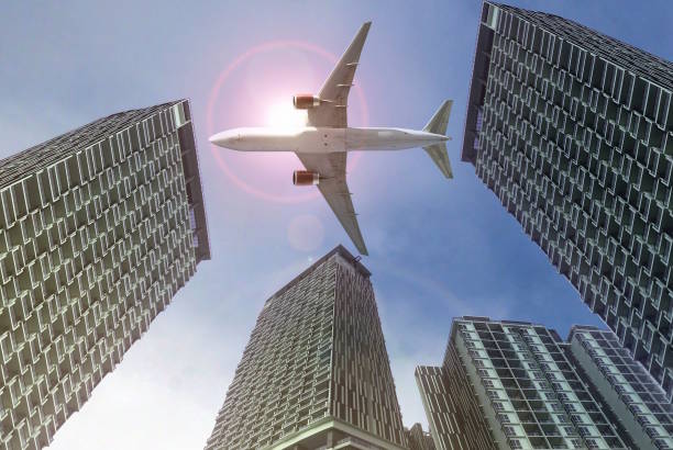 istock Airplane flying over high-rise buildings with bright sunlight in background 2029502737