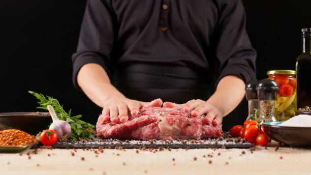 istock Chef cuts fresh meat on a wooden board on a dark background with vegetables and spices for marinade. Recipes and fresh produce concept. 2029565292