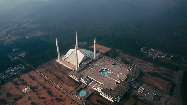 Faisal Mosque in Islamabad with surrounding landscape at dusk, serene ambiance, aerial view