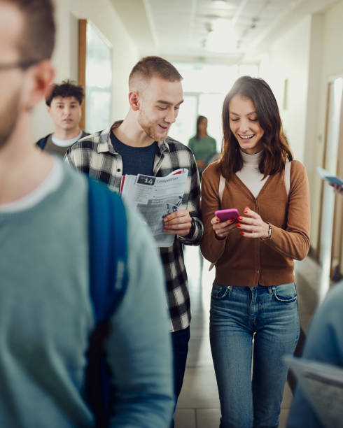 istock Happy college couple using cell phone in a hallway. 2029592027