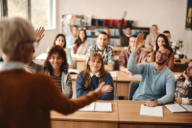 istock Happy students raising hands on a class in the classroom. 2029595688
