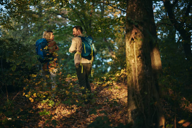 istock Back view of happy couple talking while hiking though the woods. 2029604471