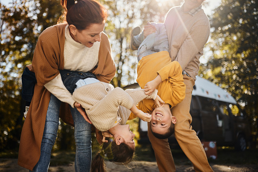 Playful parents having fun with their kids while spending an autumn day in nature.