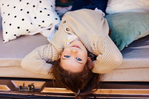 Cute little girl relaxing inside of a camper trailer and looking at camera.