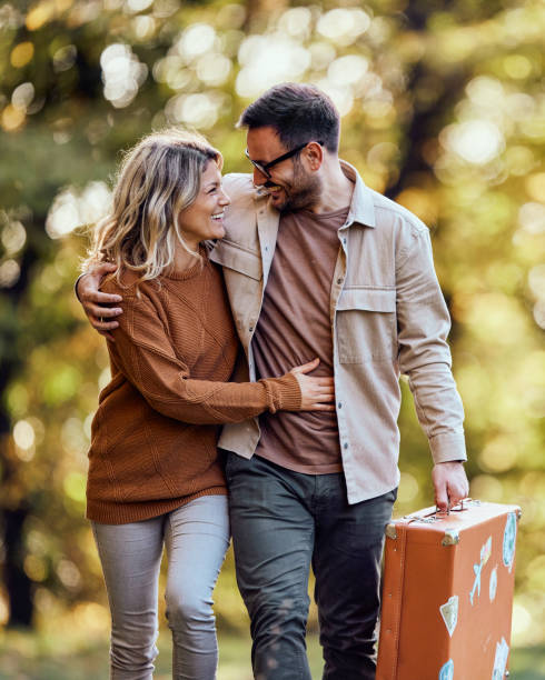 istock Happy couple talking while walking with suitcase in the park. 2029615638