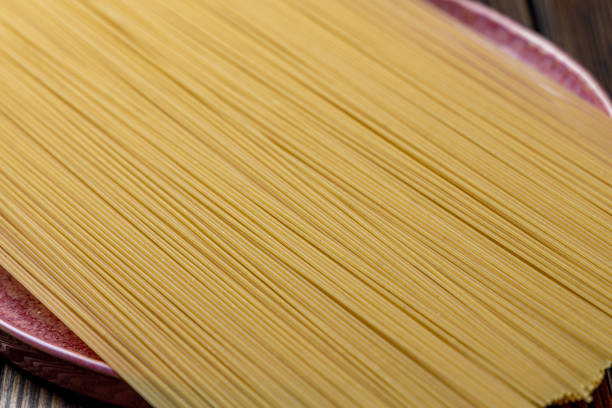 Yellow long spaghetti on a rustic background. Yellow italian pasta. Long spaghetti. Raw spaghetti bolognese. Italian food and menu concept.