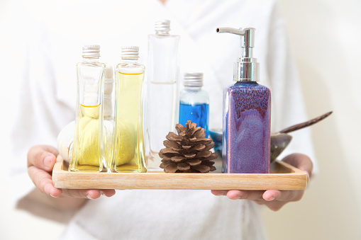 closeup masseur holding aroma herbal natural spa set oil cream wax body skin moisturizer treatment tray