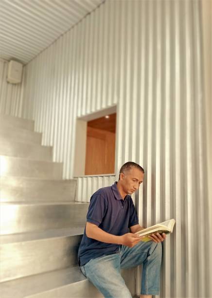 male hand choosing and picking book in public library, education research and self learning in university life concepts